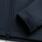 close up of navy softshell jacket zipper cuff and stitching. white background top down angle sharp focus on fabric texture and construction